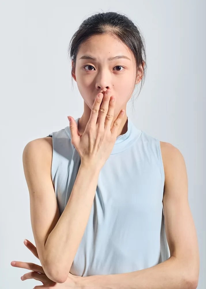 Person with a hand near their mouth